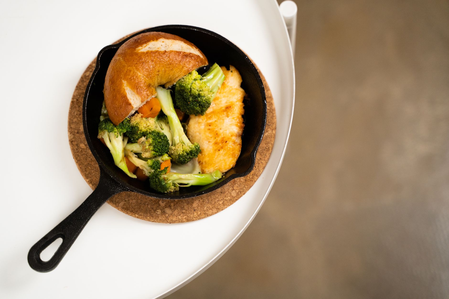 cast iron skillet care illustrated on a stovetop with oil, a towel, and a warm, seasoned pan
